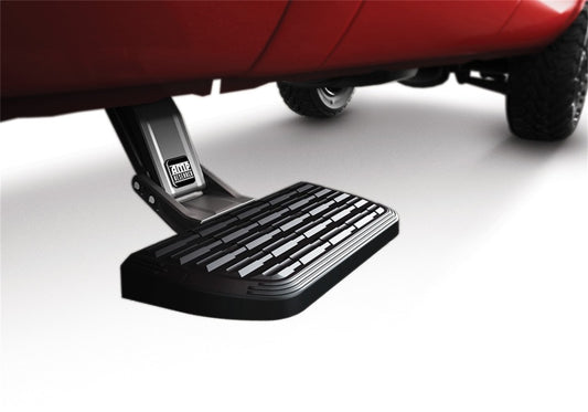 A detailed image captures the AMP Research 2023 Ford F-250/350 SuperDuty All Beds Passenger Side ONLY BedStep2 in black, extended from beneath a red vehicle. This retractable truck step showcases its textured surface for enhanced grip and is partially visible, emphasizing its robust attachment to the vehicle's chassis.