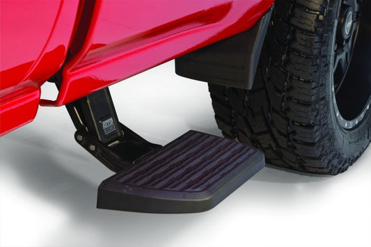 Close-up of a 2014-2017 Chevrolet Silverado 1500 showcasing an AMP Research BedStep2 in its extended position. The black, textured surface of the step is mounted above a large, rugged off-road tire. The white background highlights the Silverado's vibrant paint and the innovative design of the AMP Research step mechanism.