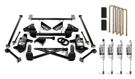 An array of automotive parts, including black metal suspension components, bolts, and brackets from the Cognito 7-Inch Standard Lift Kit With Fox PSRR 2.0 Shocks for 01-10 Silverado/Sierra 2500/3500 2WD/4WD Non-StabiliTrak by Cognito Motorsports, are laid out on a white surface. Four Fox PSRR 2.0 Performance Series shocks and a set of six gold U-bolts with rubber isolators are also displayed on the right side.
