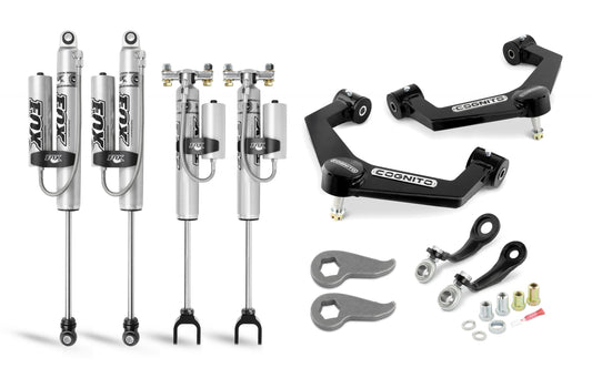 A collection of off-road vehicle suspension components, including four Fox PSRR 2.0 shocks, two Cognito upper control arms, and several small parts like screws, bolts, and adjustment tools from the Cognito 3-Inch Premier Leveling Kit by Cognito Motorsports for the 2020-2024 Silverado/Sierra 2500/3500 2WD/4WD. The Cognito components are arranged neatly against a white background.