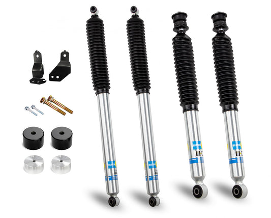 The Cognito 2-Inch Economy Leveling Kit with Bilstein Shocks for 2017-2022 Ford F250/F350 4WD Trucks, from Cognito Motorsports, includes a set of four shocks each featuring a black coil over a silver body adorned with blue and yellow markings. The package also contains essential components such as black brackets, metal bolts, and cylindrical spacers, perfect for setting up a leveling kit. All items are displayed against a plain white background.