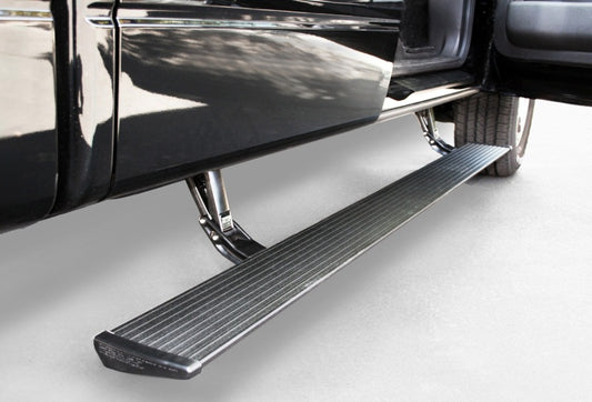 The AMP Research 2009-2014 Ford F150 All Cabs PowerStep - Black is an electric-powered running board that extends at the door of a sleek black vehicle. It features a textured surface for grip and sits next to a large tire on smooth gray pavement, providing all-weather performance.