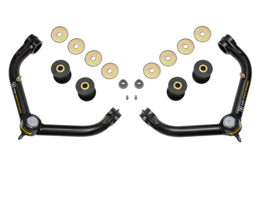 The ICON 01-10 GM HD Tubular Upper Control Arm Delta Joint Kit by ICON showcases two black upper control arms with heavy-duty ball joints, complemented by eight round metallic discs, four cylindrical bushings, and two small bolts, all symmetrically arranged on a white background.