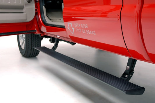 A red Ford vehicle with the door open displays an AMP Research black PowerStep running board, which extends automatically below. The message "Open door, step on board" is marked with a downward arrow. The interior and part of the tire are visible.
