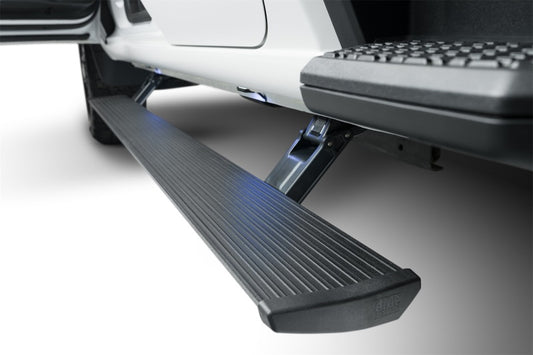 A close-up view showcases the AMP Research 23-24 Chevrolet Colorado / GMC Canyon Crew Cab PowerStep Plug N Play - Black, extended from the side of a vehicle. The black, textured automatic running board beneath the open door emphasizes its all-weather performance and sleek design.