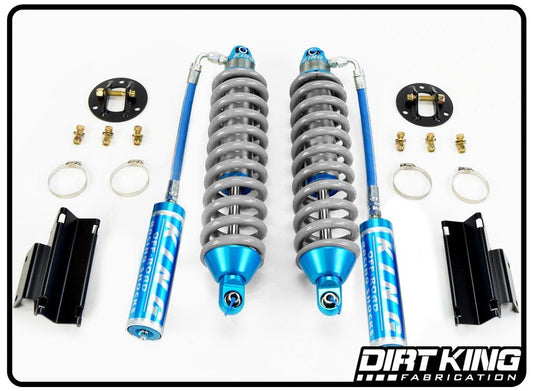 A set of Dirt King Ford F-150 Long Travel Spec King Coilovers, featuring blue and silver components along with accompanying hardware, brackets, and mounting rings, is displayed on a white background. The "DIRT KING SHOCKS" logo is in the bottom right corner, showcasing their commitment to top-notch off-road performance.
