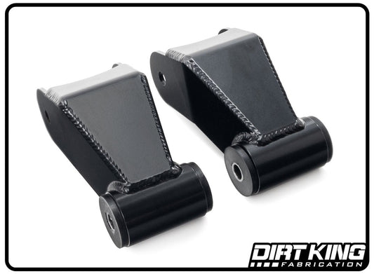 A pair of 99-18 GM 1500 Long Travel Shackles from DIRT KING, constructed from black metal with cylindrical attachments and featuring detailed welding lines and built-in grease ports. Displayed on a white background and framed by a black border, the logo "Dirt King Fabrication" is positioned at the bottom right corner.